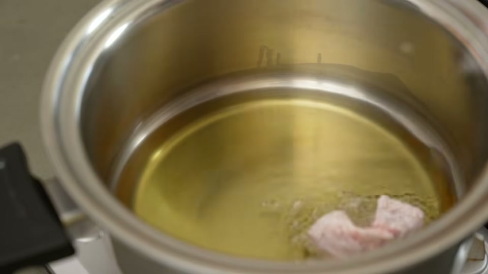 大きめに切った豚肉を鍋に入れる場面