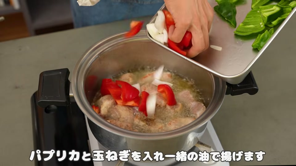 肉の揚げ焼き中にパプリカと玉ねぎを投入