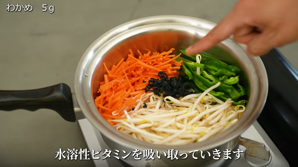 ステンレス鍋に野菜を敷き詰め上に乾燥わかめを乗せるシーン
