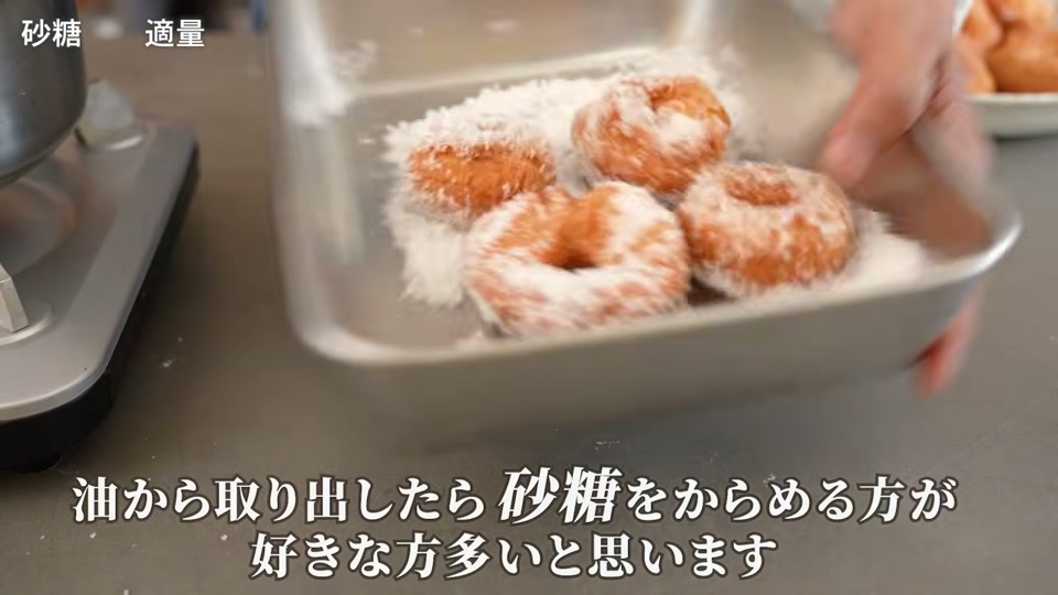 揚げたてドーナツに砂糖を絡める場面
